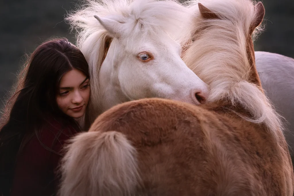 Inniges Kuschel Foto von zwei Shetland Ponies und einer jungen Frau, sehr ausdrucksstark und naturnah, aufgenommen auf einer Weide im Ruhrgebiet (NRW) durch die Pferdefotografin Anne Bertling aus Ascheberg bei Münster im Münsterland.